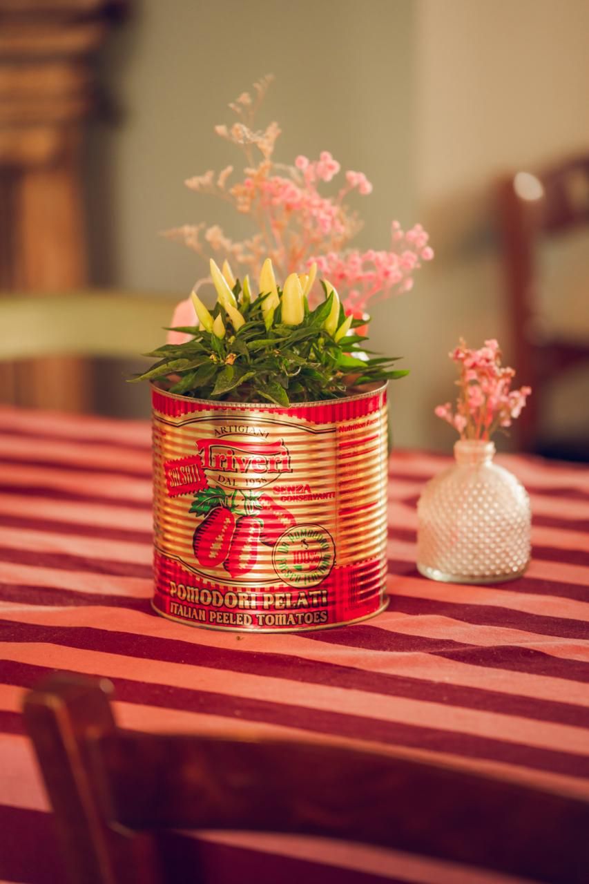 Fiori in un barattolo di pomodori sul tavolo a righe